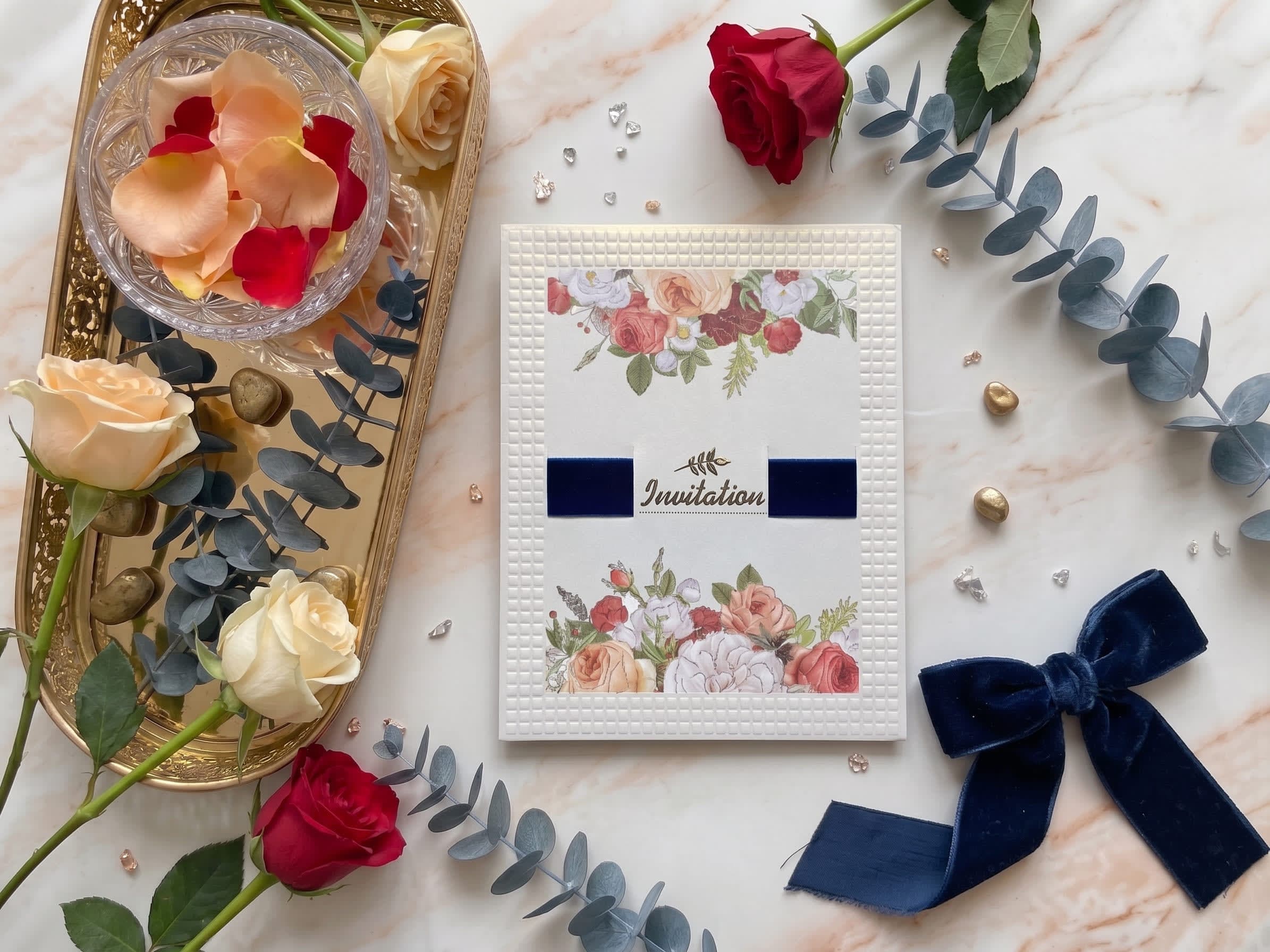 Cream wedding invitation card with an embossed grid texture, navy velvet band and rose clusters by Shahi Bulawa Karachi